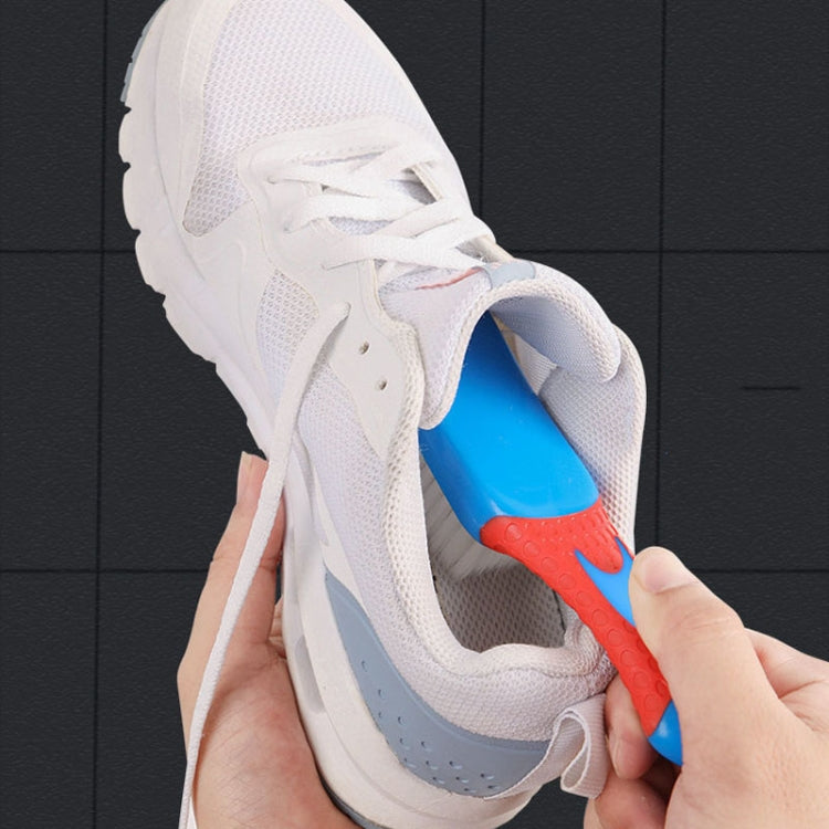 Hand using red-and-blue brush on a white sneaker