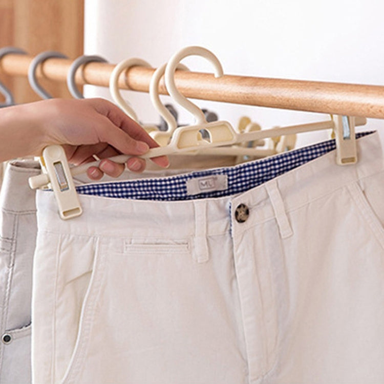 Hand placing trousers on a 360° rotatable pants hanger with anti-slip clips