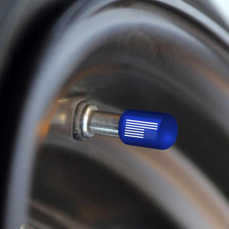 Blue aluminum tire valve dust cap installed on wheel rim, showing vent-like stripe pattern