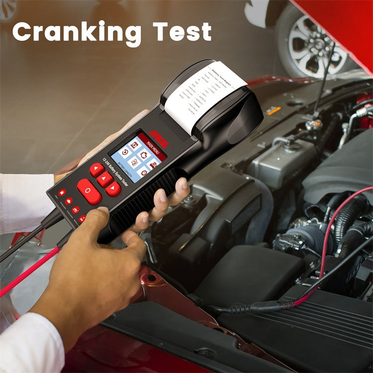 Handheld battery tester connected with red/black cables for a cranking test in engine bay