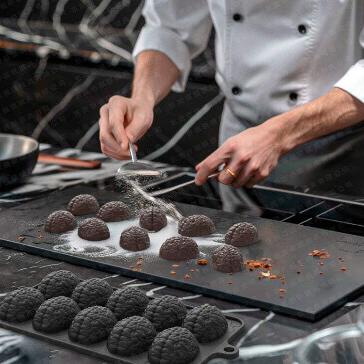 Chef filling brain-shaped cavities in a dark silicone chocolate mold tray