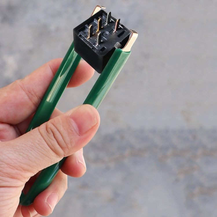 Hand using green double-hook plug extraction tweezers on an electronic connector