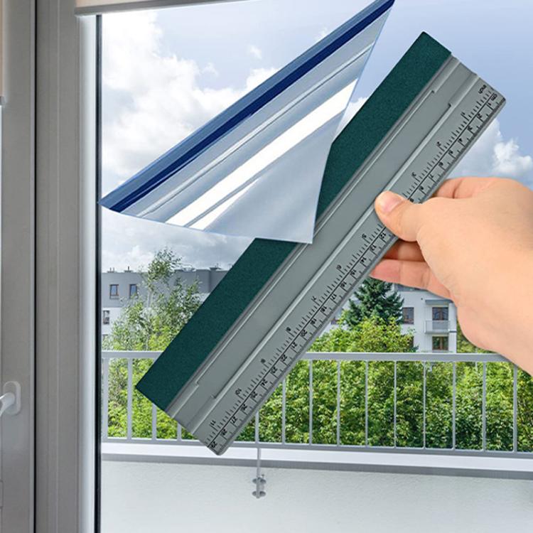 Window scraping tool with teal felt pad held along frame, gray measurement scale visible