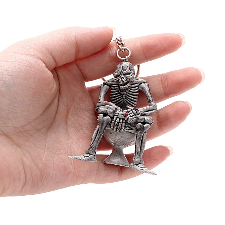 Skeleton skull keychain with red-eyed detail, chain and loop ring, held in hand