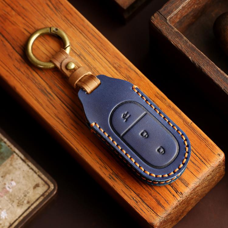 Blue genuine leather car key cover with brass keyring on wooden surface and stitched design