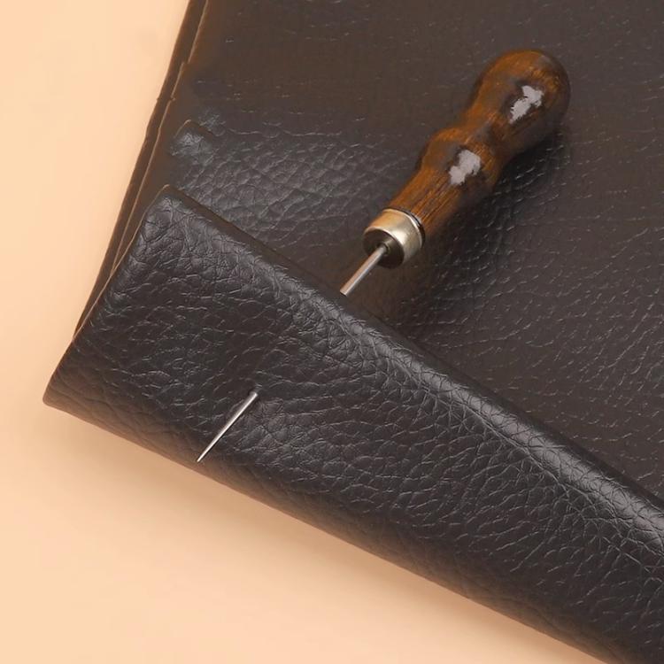 Leather repair awl inserted into dark leather with wooden handle and steel needle