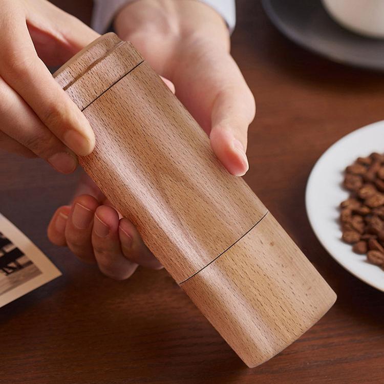 Light wooden hand coffee grinder with crank handle, held by two hands