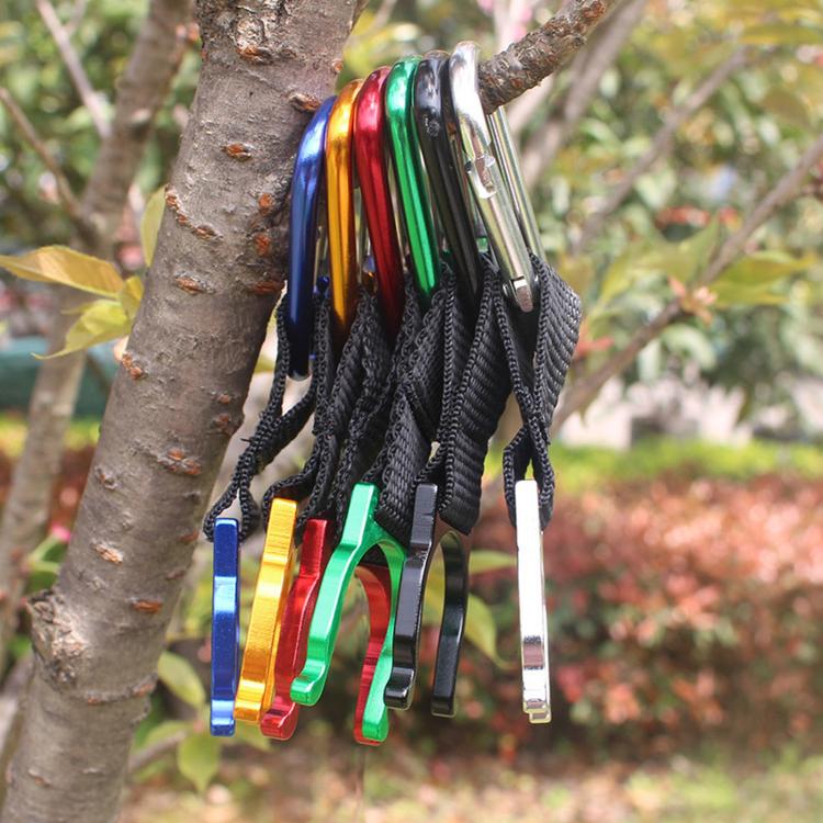 Assorted colorful metal bottle holder clips with black straps hanging on tree