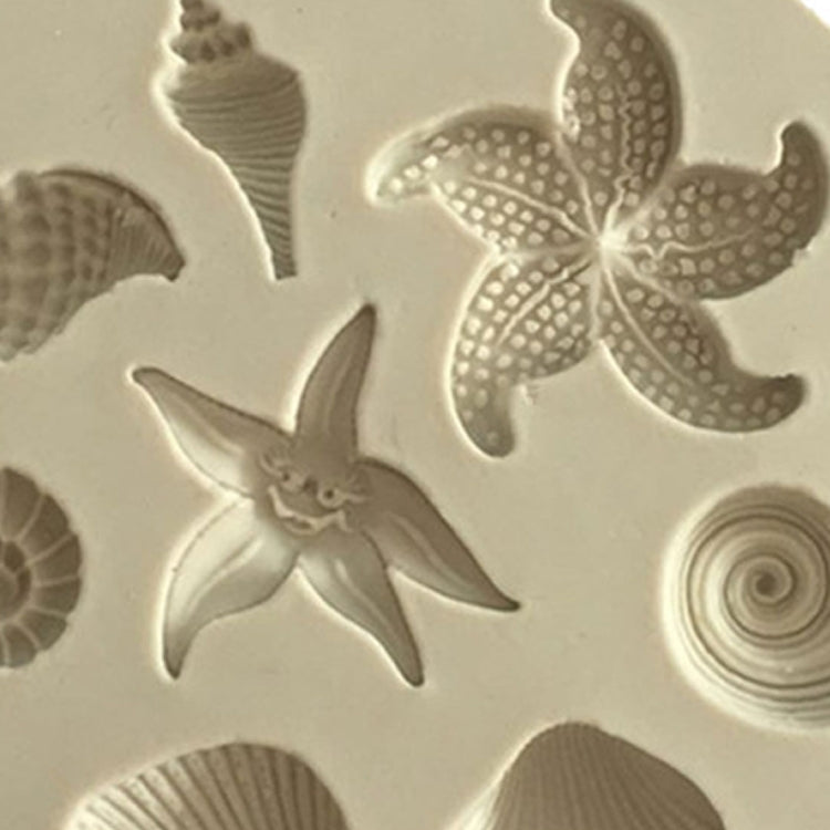 Close-up of round silicone mold showing sea star, shells, and spiral conch relief