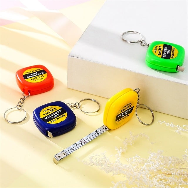 Retractable tape measure key rings in green, orange, blue, and yellow with metal loops; tape out