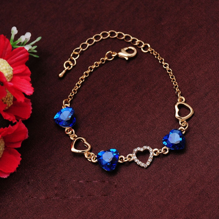 Gold-tone heart charm bracelet with blue crystals and heart toggle clasp
