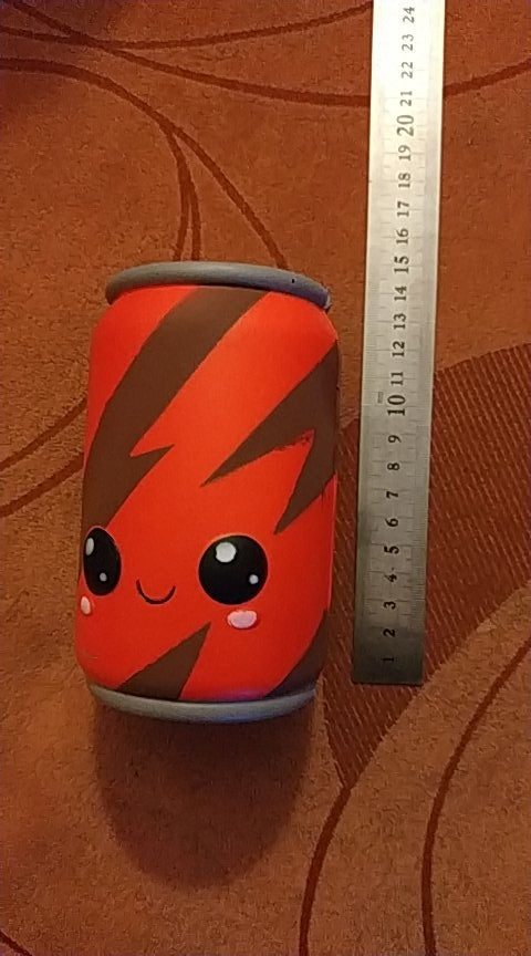 Red squishy can toy with measuring ruler beside it