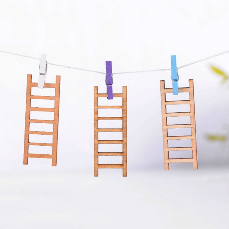 Three mini wooden ladders hanging on a string with blue and purple clothespins