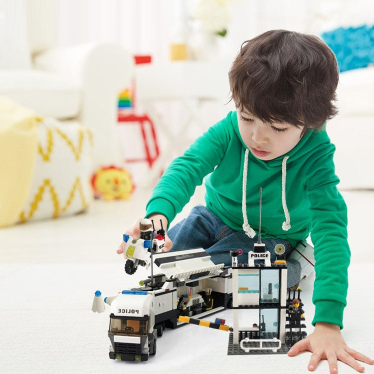 Child playing with police station building set, including police truck and officer minifigures.