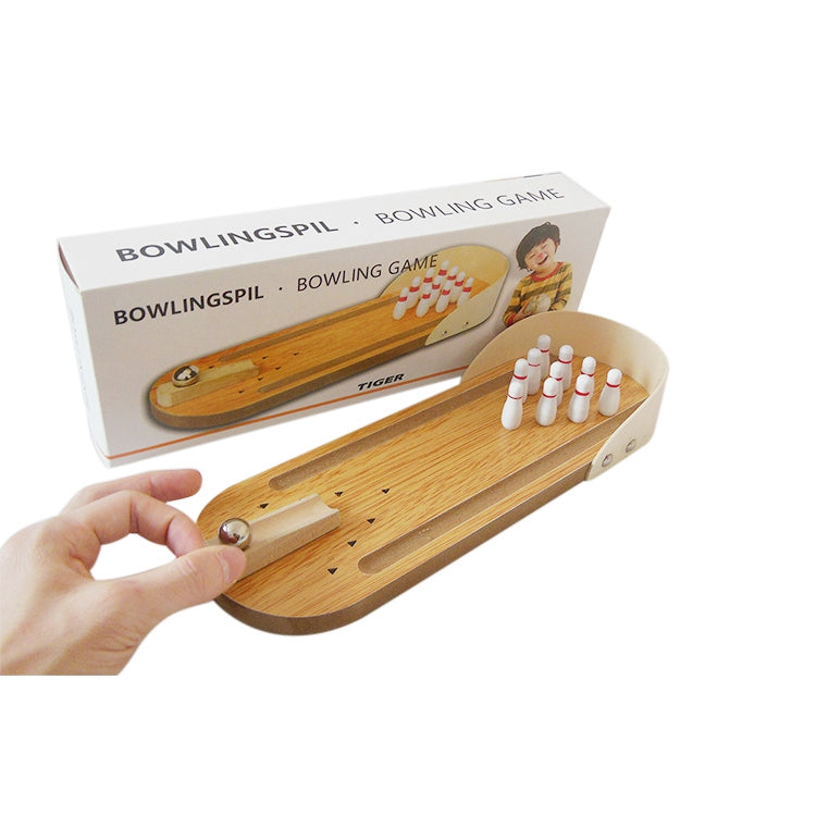 Hand placing a metal ball on a wooden mini bowling lane with pins
