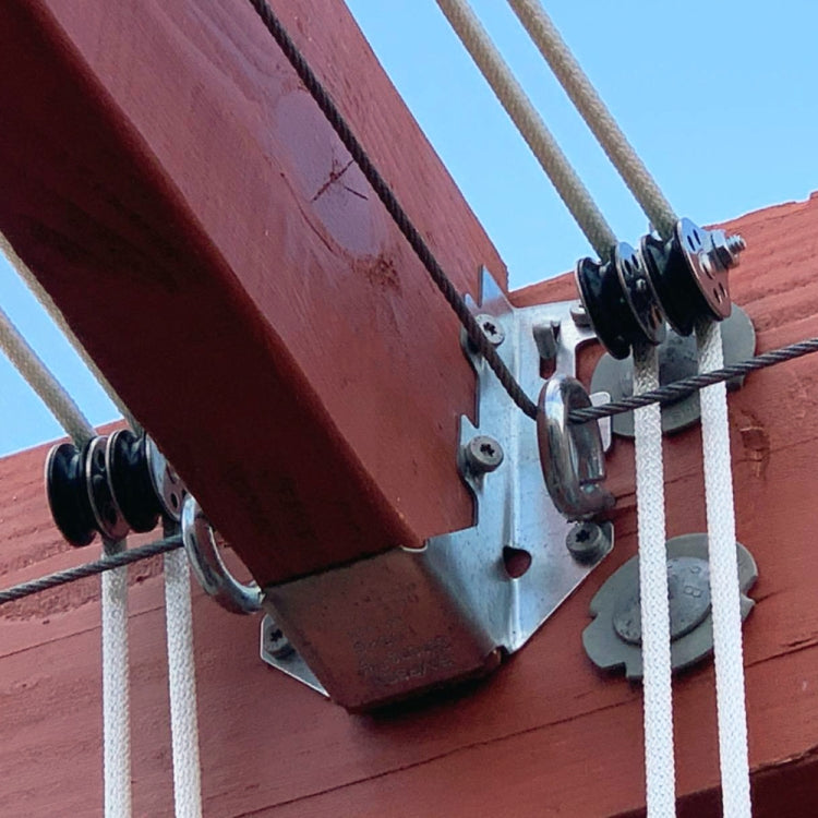 Stainless steel yacht pulley mounted on wooden beam with rope passing through