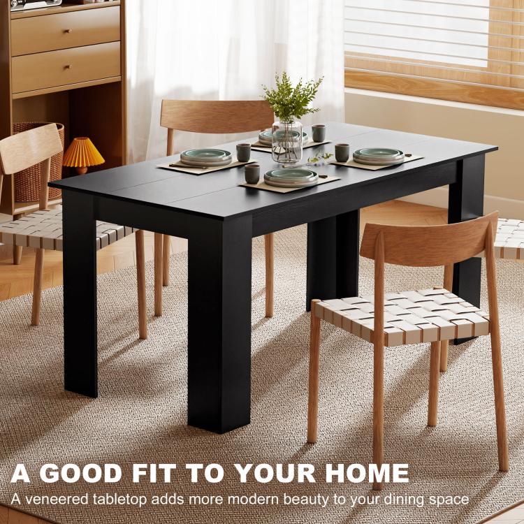 Black rectangular dining table with place settings and squared legs in a room