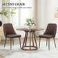 Two brown accent dining chairs with high backs and black metal legs around a round table