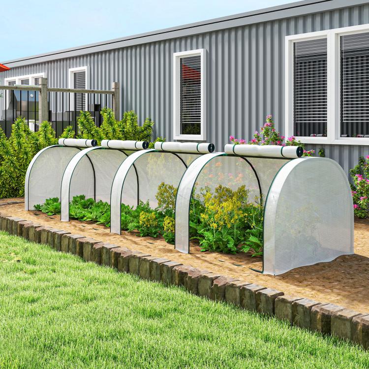 Portable tunnel greenhouse with white mesh end panels and arched frame in a garden row
