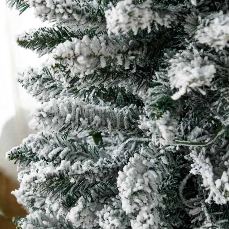 Snow-dusted slim artificial Christmas tree branches with realistic green needles