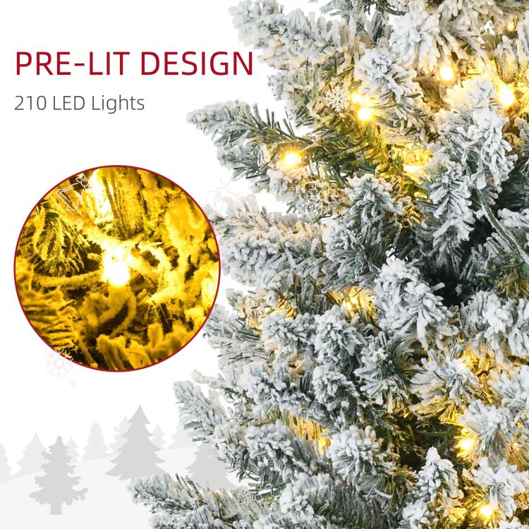 Snow-dusted artificial Christmas tree branches with warm white lit bulbs