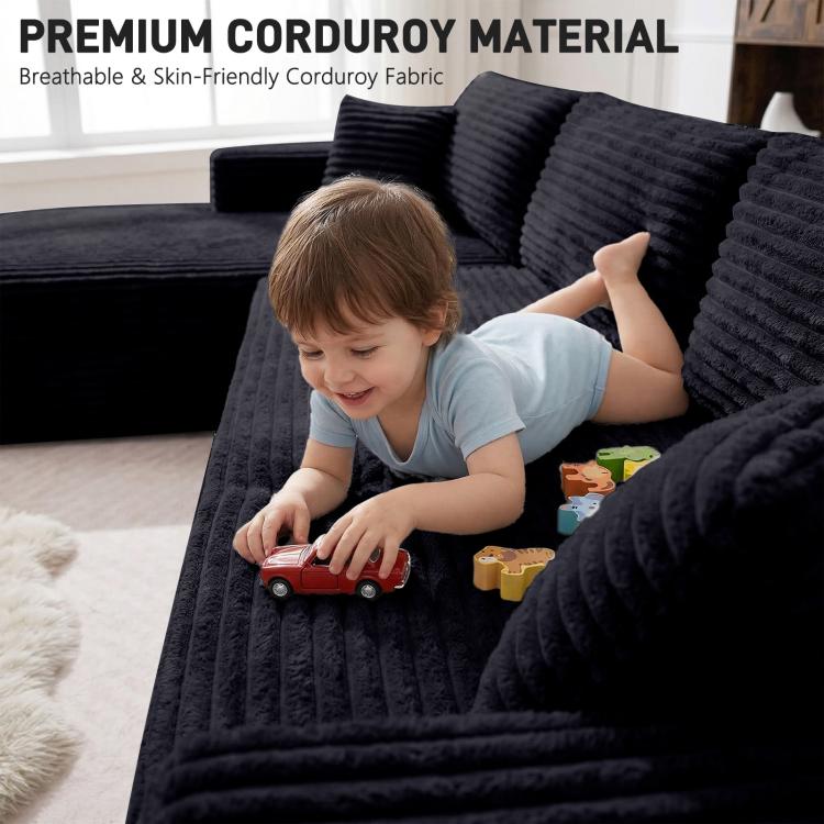 Black corduroy sectional sofa with deep seats and wide arms, shown with child