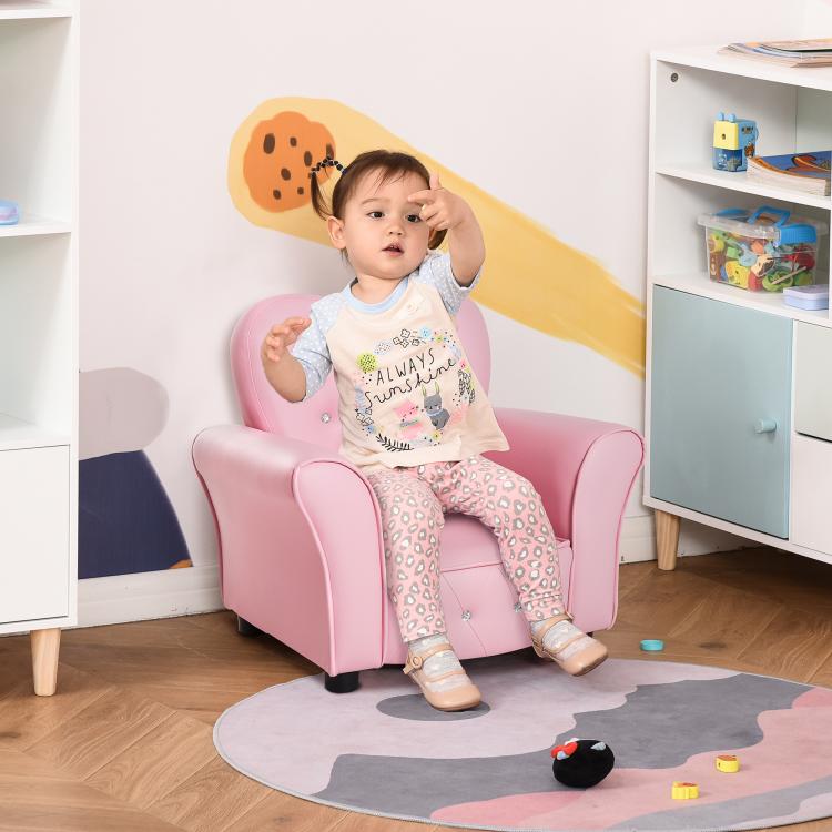 Pink toddler sofa chair with child seated; tufted heart backrest and rhinestone buttons