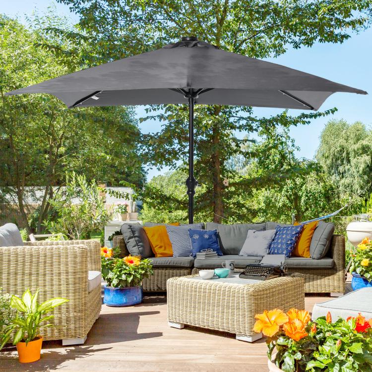 Gray outdoor patio umbrella with solar LED lights over lounge seating