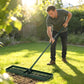 Lawn leveling rake in use on grass bed, with person pushing the green frame