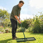Lawn leveling rake with ridged base on grass, held by a person outdoors