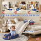 Toddler using blue-and-white extra-length slide on carpet near bed