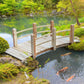 Wooden garden bridge with railings across a pond