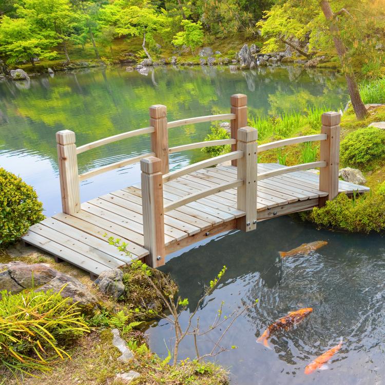 Wooden garden bridge with railings across a pond