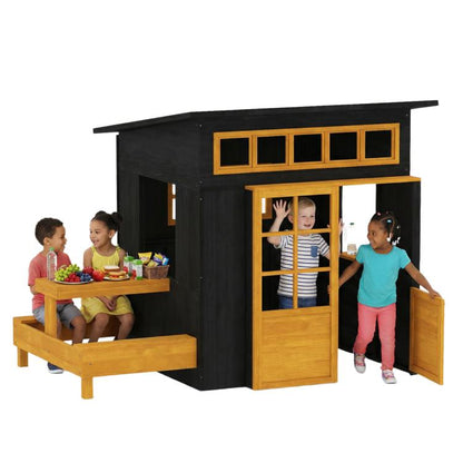 Black wooden outdoor playhouse with half-door opening, windows, and attached picnic table