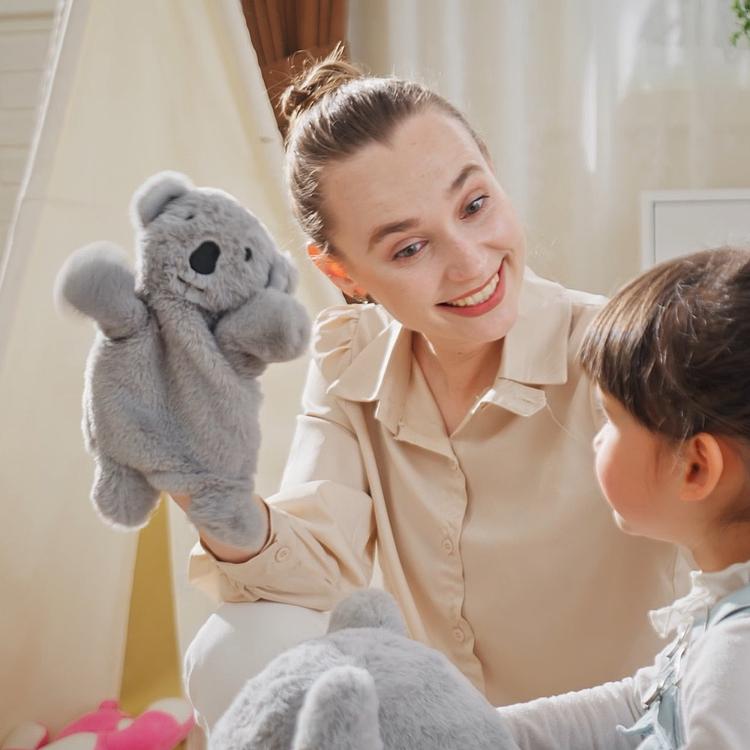 Gray koala rocking horse plush doll with child holding it indoors