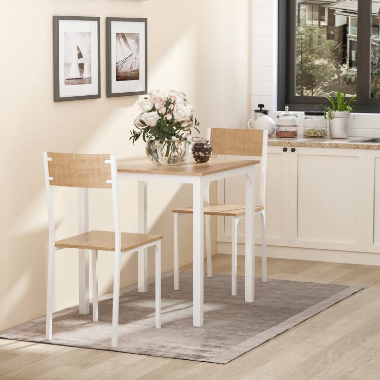White dining table set with square tabletop and two wood-tone chairs in a room.