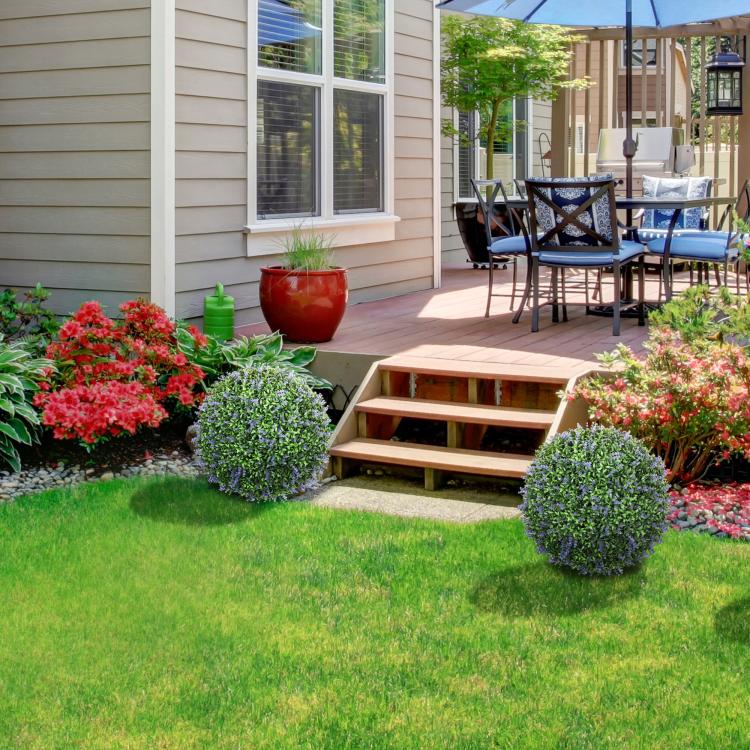 Artificial topiary balls in landscaping beds alongside bright red and green plants