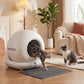 White enclosed cat litter box with round doorway and gray litter mat, cats nearby