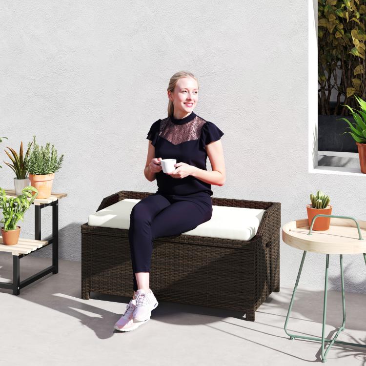 Outdoor wicker storage bench with cushioned seat, light cream top, dark brown woven sides