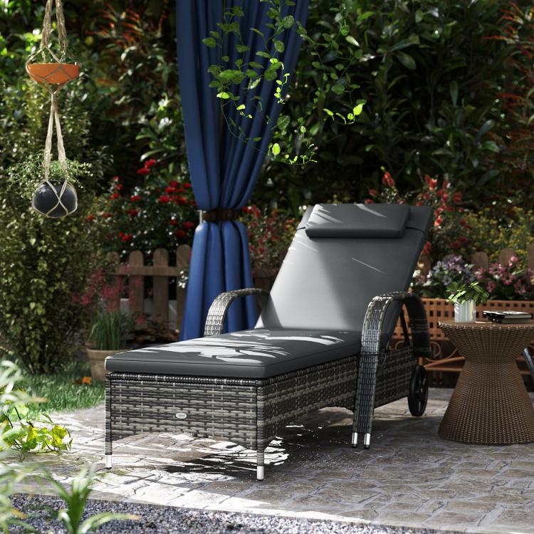 Outdoor chaise lounge chair with gray cushion and headrest on a woven rattan frame