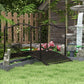 Dark bronze arched garden bridge with scroll side rails on lawn and stone border.