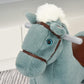 Blue plush rocking horse head with brown bridle and white mane, close-up