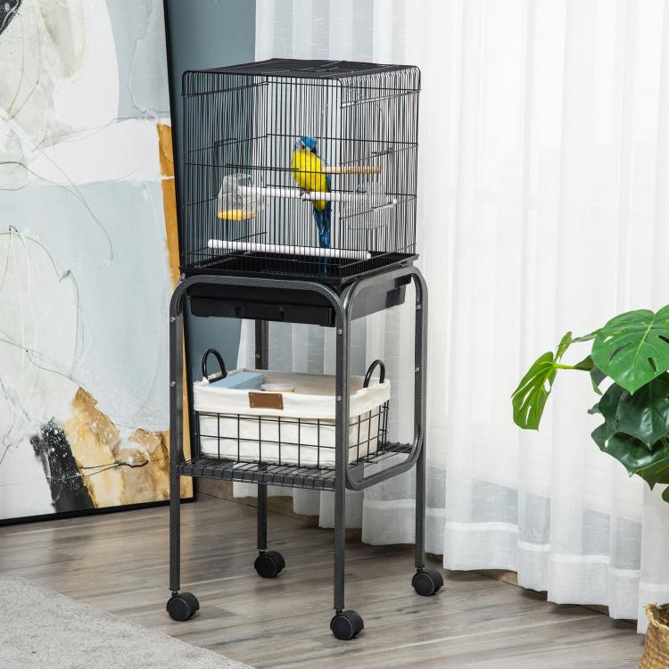 Black metal indoor bird cage on rolling stand with front access panel and storage basket