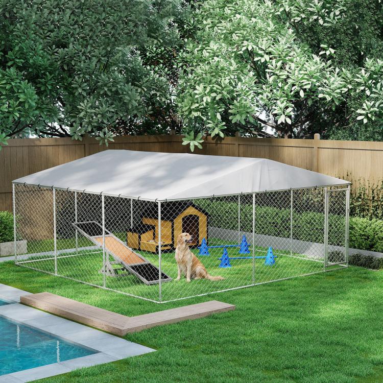 Outdoor dog kennel with silver frame, gray waterproof roof, chain-link walls around grassy backyard area