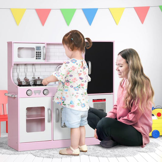 Pink kids pretend play kitchen with stovetop and sink, seen beside playing child