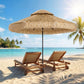 Khaki thatched patio umbrella with straw fringe and black center pole, open over patio