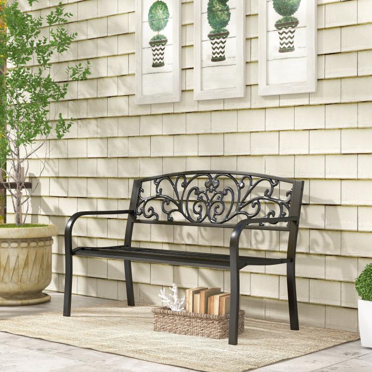 Black metal garden bench with decorative scrollwork backrest and curved armrests
