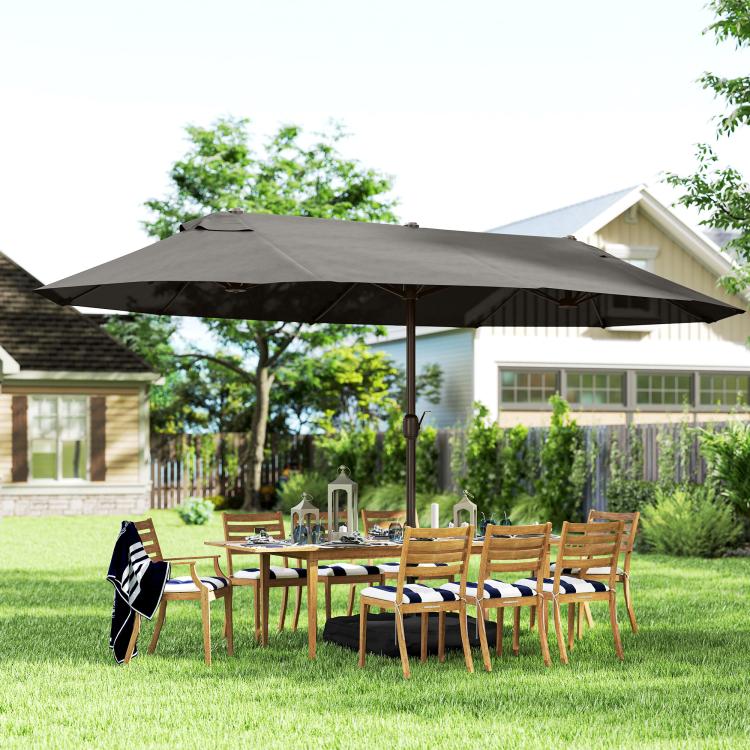 Dark gray rectangular patio market umbrella standing over outdoor chairs and table