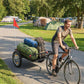 Bike cargo trailer with green and rolled gear in the black bed, on pneumatic wheels