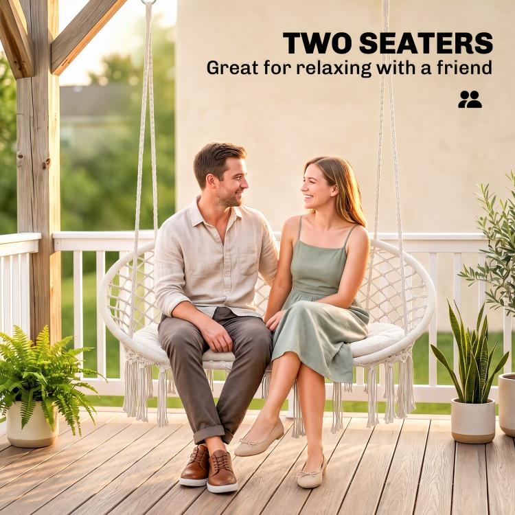 Two-person hanging hammock chair with macrame seat and cream cushion on patio